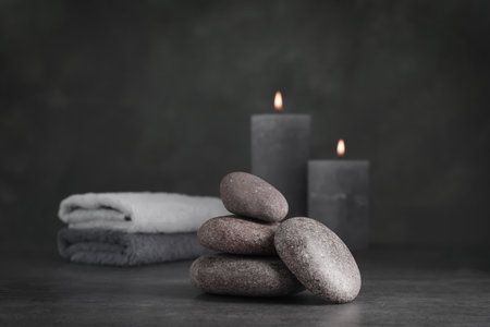 Spa stones with candles and towels on gray tableの写真素材