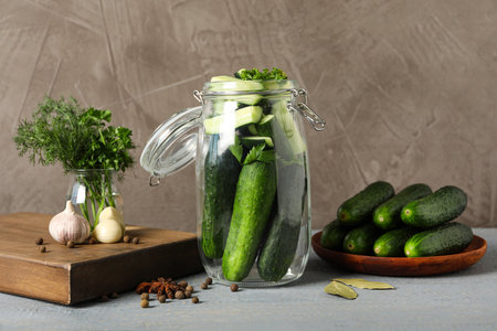 Pickling jar with fresh ripe cucumbers on gray wooden tableの写真素材