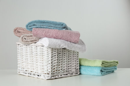 Wicker basket with clean soft towels on light backgroundの写真素材
