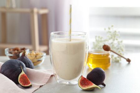 Delicious fig smoothie in glass on light tableの写真素材