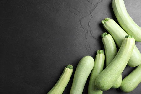Raw green zucchinis on black slate table, flat lay. Space for textの写真素材