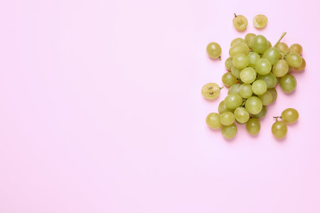 Bunch of ripe green grapes on pink background, flat lay. Space for textの写真素材