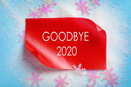 Text Goodbye 2020 and artificial snow on light blue background, flat layの写真素材