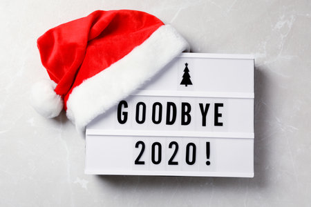 Lightbox with text Bye Bye 2020! and Santa hat on light gray background, flat layの写真素材