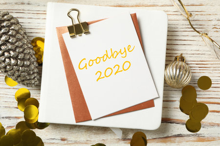 Card with text Goodbye 2020 and festive decor on wooden background, flat layの写真素材
