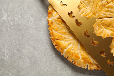 Traditional galette des Rois with paper crown on light gray table, flat lay. Space for textの写真素材