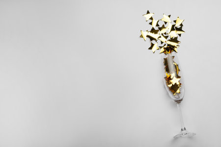 Flat lay composition with confetti and champagne glass on light background. Space for textの写真素材