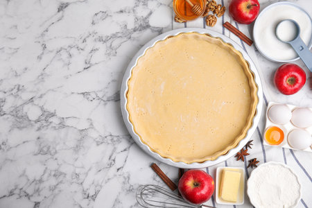 Raw dough and traditional English apple pie ingredients on white marble table, flat lay. Space for textの写真素材