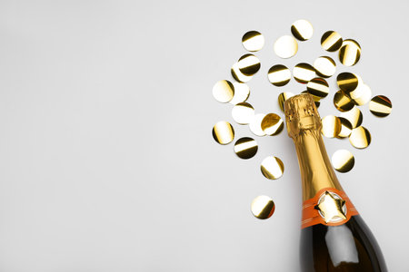 Flat lay composition with confetti and bottle of champagne on light background. Space for textの写真素材