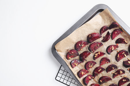 Baking tray with roasted beetroot slices on white table, top view. Space for textの写真素材