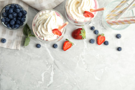 Tasty milk shakes with fresh berries on gray marble table, flat lay. Space for textの写真素材