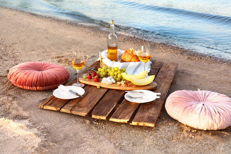 Food for picnic and white wine served on wooden pallet near riverの写真素材