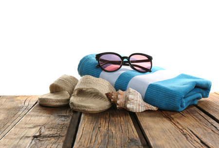 Towel, sunglasses, shoes and sea shell on wooden table. beach accessoriesの写真素材