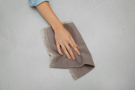 Woman wiping gray table with kitchen towel, top viewの写真素材