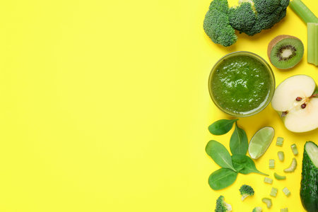 Delicious green juice and fresh ingredients on yellow background, flat lay. Space for textの写真素材