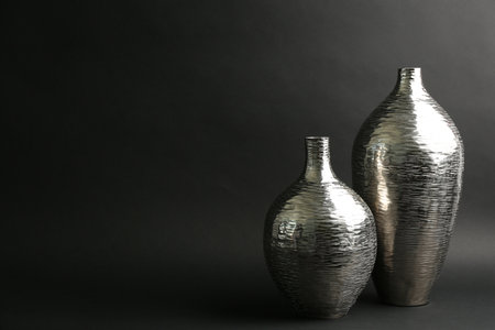 Stylish silver ceramic vases on black background, space for textの写真素材