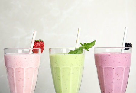 Tasty milk shakes with fresh berries and mint on light background, closeupの写真素材