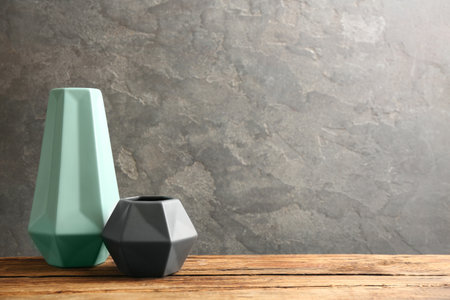 Stylish empty ceramic vases on wooden table against gray background. Space for textの写真素材