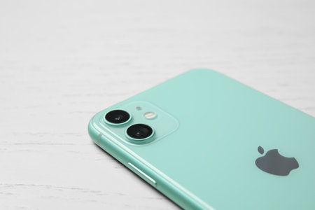 MYKOLAIV, UKRAINE - JULY 10, 2020: New modern Iphone 11 Green on white wooden table, closeup