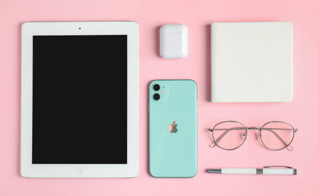 MYKOLAIV, UKRAINE - JULY 10, 2020: Flat lay composition with Iphone 11, iPad tablet and AirPods on pink backgroundのeditorial素材