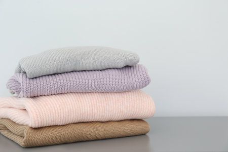Stack of folded warm knitted sweaters on gray tableの写真素材
