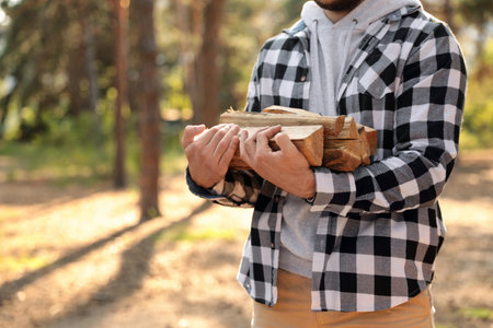 Man with cut firewood in forest, closeupの写真素材