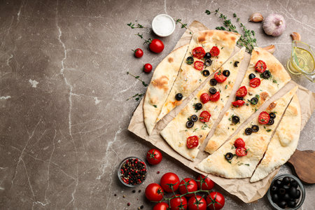 Delicious focaccia bread with olives and tomatoes on marble table, flat lay. Space for textの写真素材
