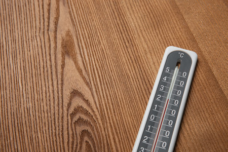Weather thermometer on wooden table, closeup. Space for text