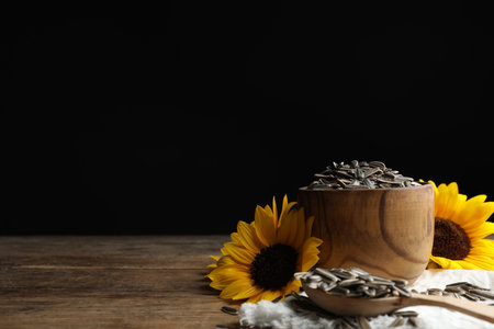 Organic sunflower seeds and flowers on wooden table. Space for textの写真素材