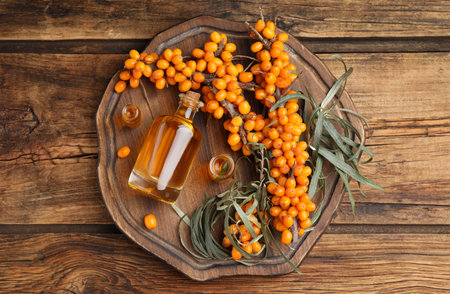 Natural sea buckthorn oil and fresh berries on wooden table, top viewの写真素材