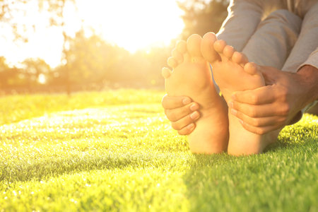 Man sitting barefoot on fresh green grass outdoors, closeupの写真素材