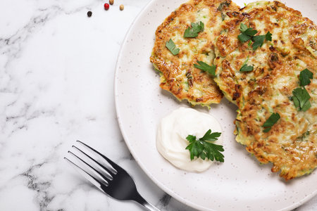 Delicious zucchini fritters served on white marble table, flat layの写真素材
