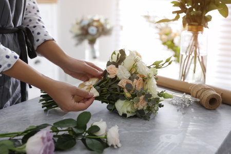 Florist tieing bow of beautiful wedding bouquet at light gray marble table, closeupの写真素材