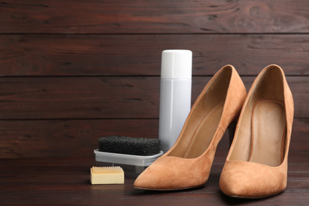 Stylish footwear with shoe care accessories on brown wooden table. Space for textの写真素材