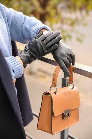 Young woman with stylish black leather gloves and bag outdoors, closeupの写真素材