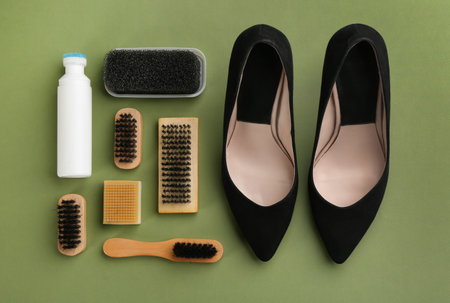 Stylish footwear with shoe care accessories on green background, flat layの写真素材