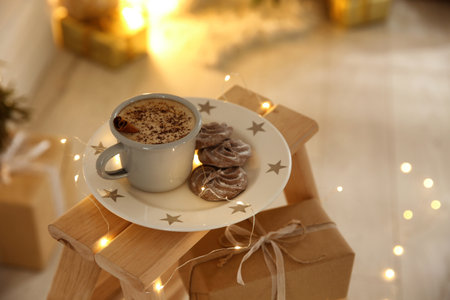 Tasty hot drink, chocolate cookies and Christmas lights indoors. Space for textの写真素材