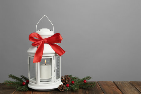 Decorative Christmas lantern with bow and coniferous twigs on gray background. Space for textの写真素材