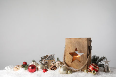 Composition with wooden Christmas lantern on snow against light gray background, space for textの写真素材