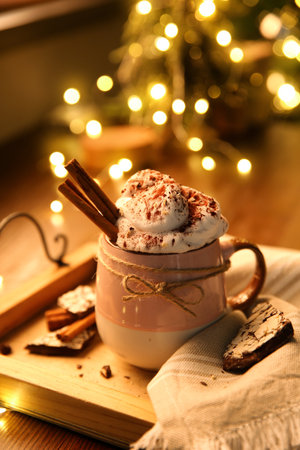 Tasty hot drink with whipped cream and Christmas lights on tableの写真素材