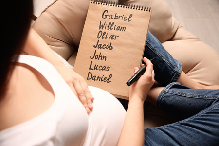 Pregnant woman with baby names list sitting in armchair, closeupの写真素材