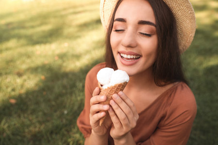 Happy young woman with delicious ice cream in waffle cone outdoorsの写真素材