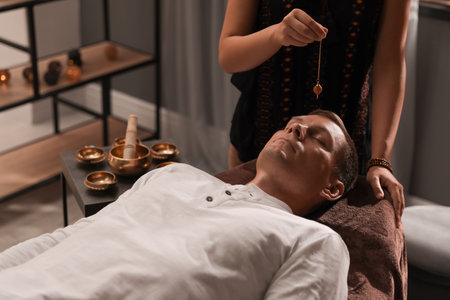 Man at crystal healing session in dark roomの写真素材