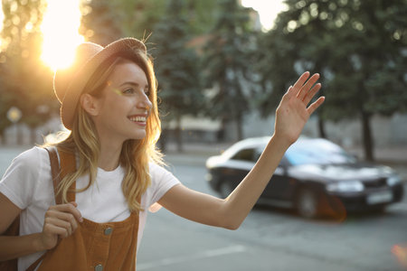 Young woman catching taxi on city streetの写真素材