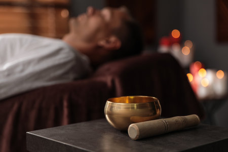 Man at healing session in dark room, focus on singing bowlの写真素材