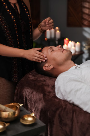 Man at crystal healing session in dark roomの写真素材