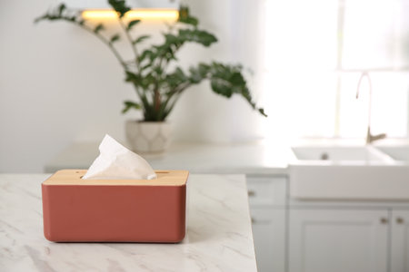 Box with paper tissues on white marble table in kitchen. Space for textの写真素材