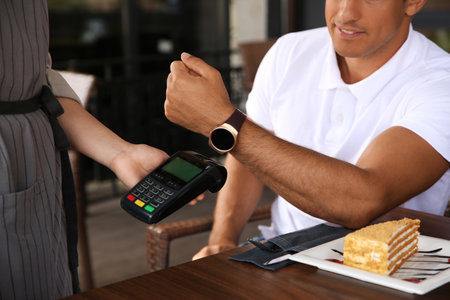 Man making payment with smart watch in cafe, closeupの写真素材