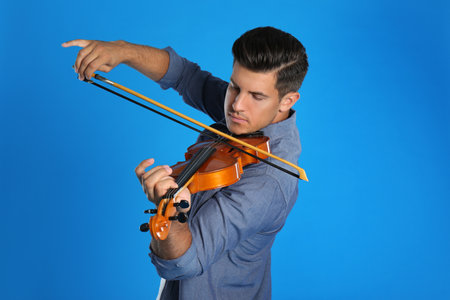 Man playing violin on light blue backgroundの写真素材