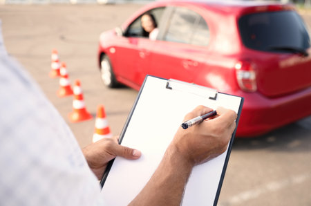Instructor with clipboard near car outdoors, closeup. driving school examの写真素材